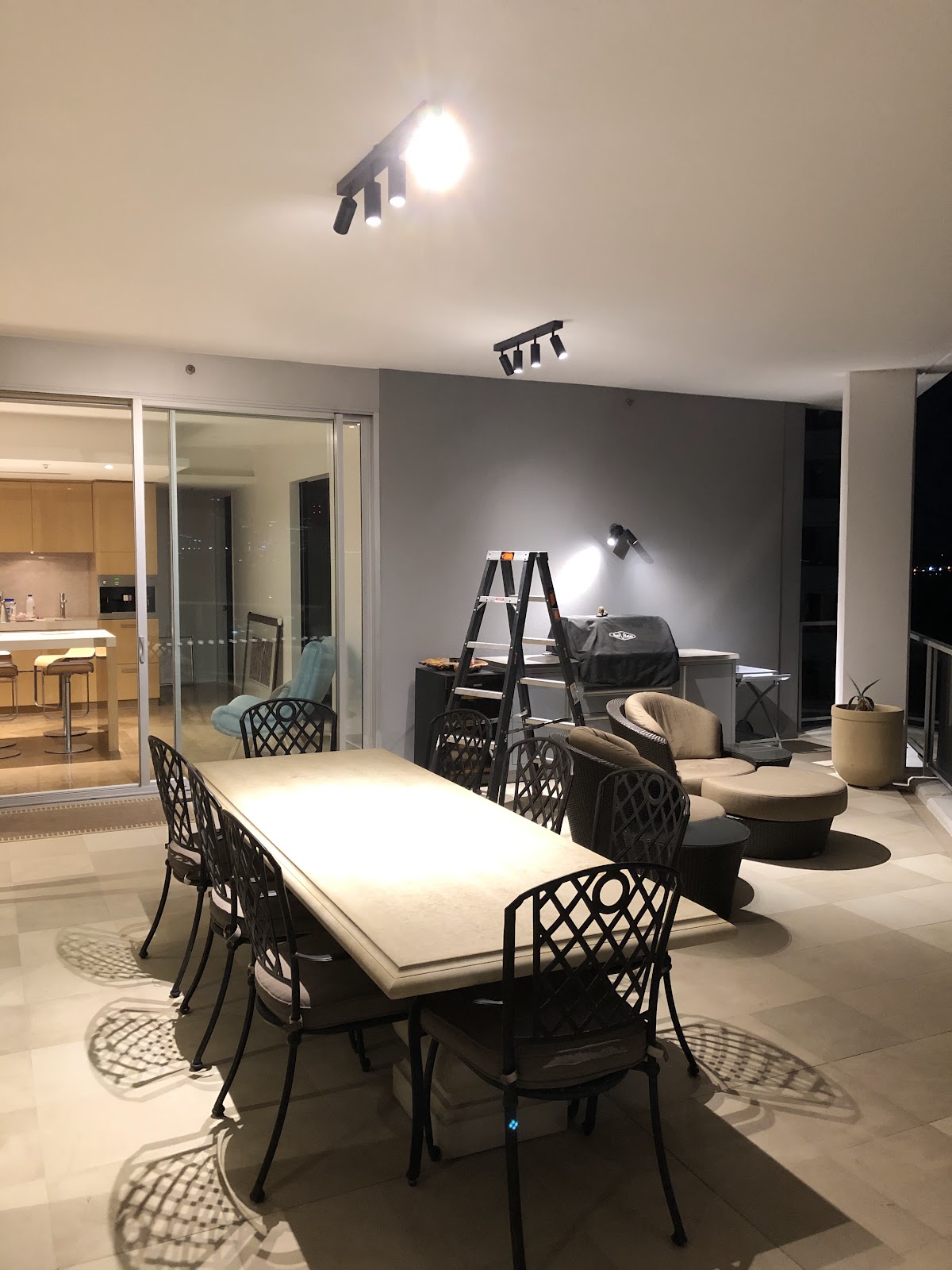Black track spotlights over an outdoor dining area on a balcony