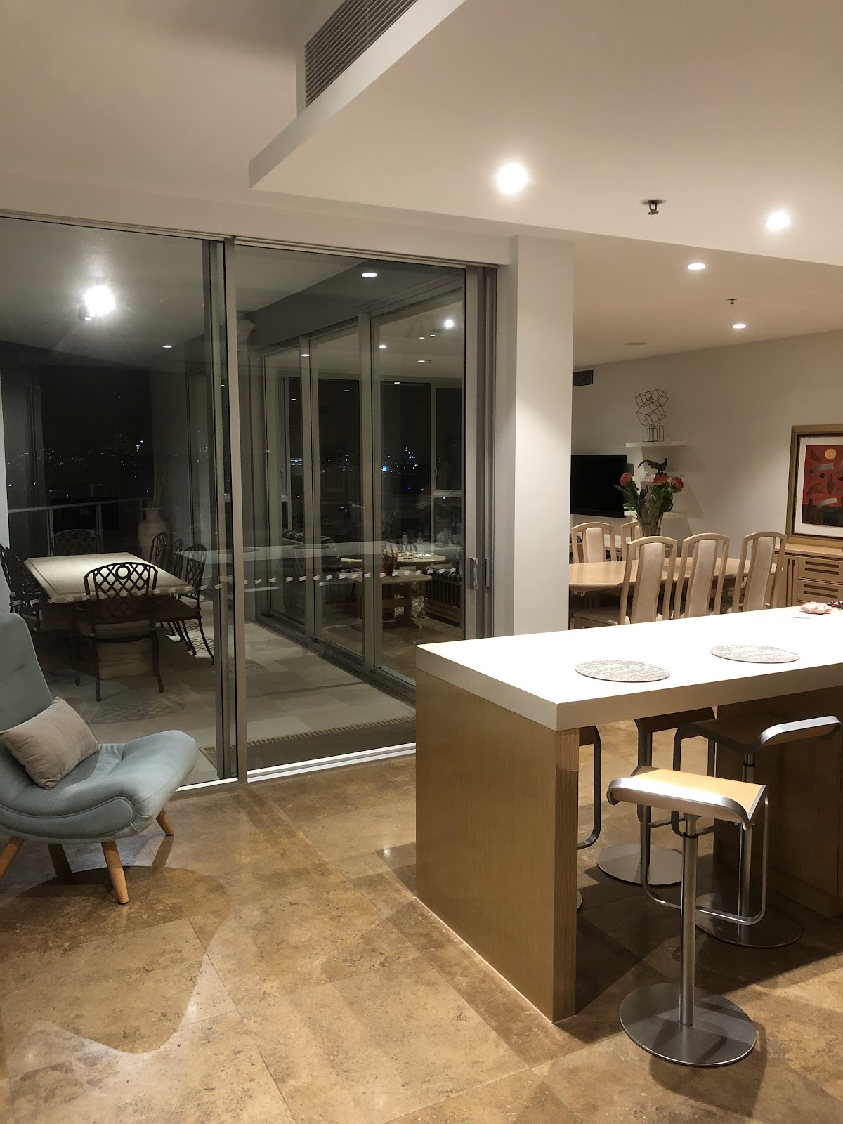 Downlights over a stone kitchen bench, night view out the glass